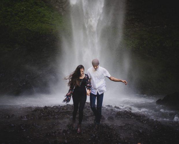 Engagement photography at Latourell Falls in the Columbia River Gorge near Portland, Oregon of a stylish couple walking away from a waterfall.