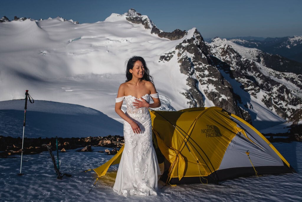 Bride emerging from tent on snowy mountain top