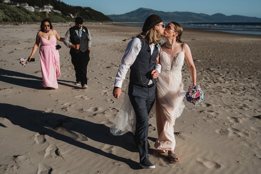 Bride and groom on beach with wedding party 