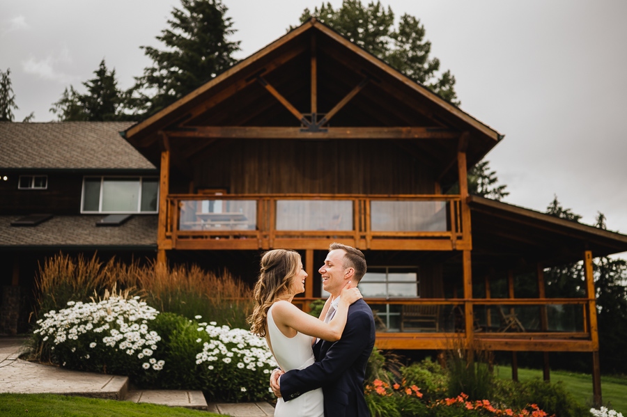 Bride and groom romantically wrap their arms around each other in front of their wedding venue, Scholls Valley Lodge.