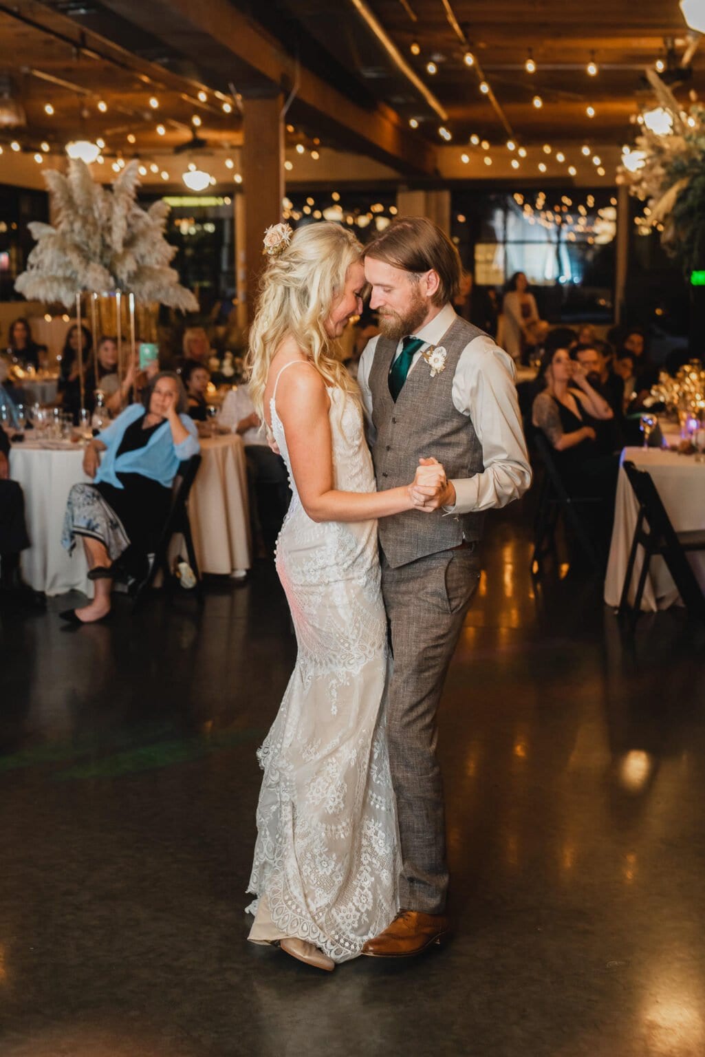 A couple shares a first dance at their wedding reception at Castaway Portland, surrounded by guests and warm, ambient lighting.
