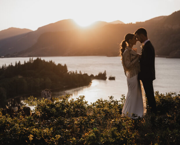 Newlyweds cuddle together on a cliff at The Griffin House overlooking the Columbia River Gorge at sunset.l