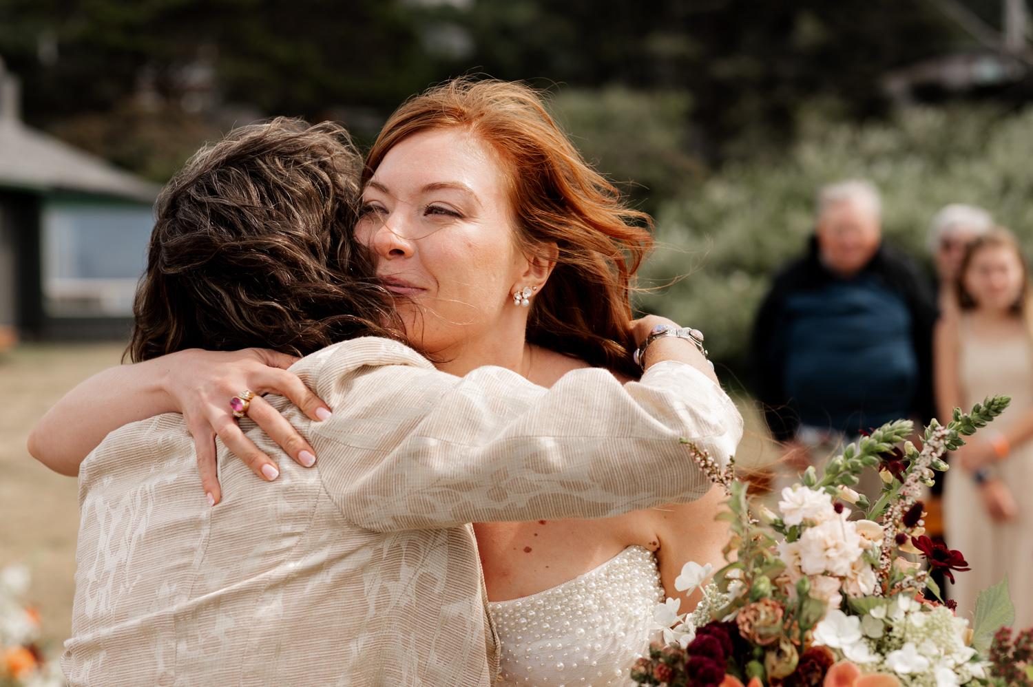 Two people embracing at an outdoor wedding surrounded by lush greenery and vibrant flowers at the Yachats Inn.