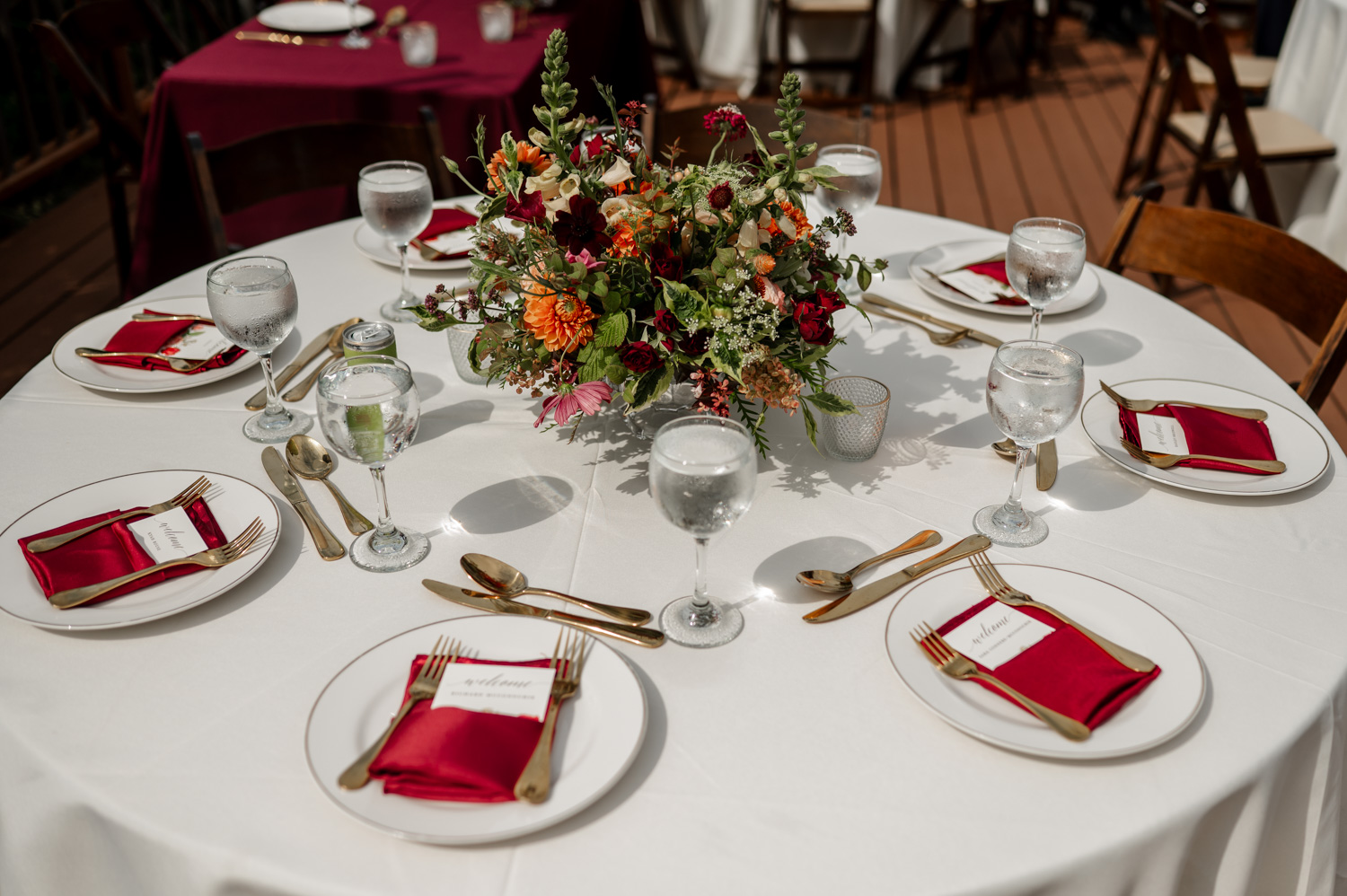 A table setting with a white tablecloth, floral centerpiece, red napkins, and gold cutlery at the Yachats Inn.