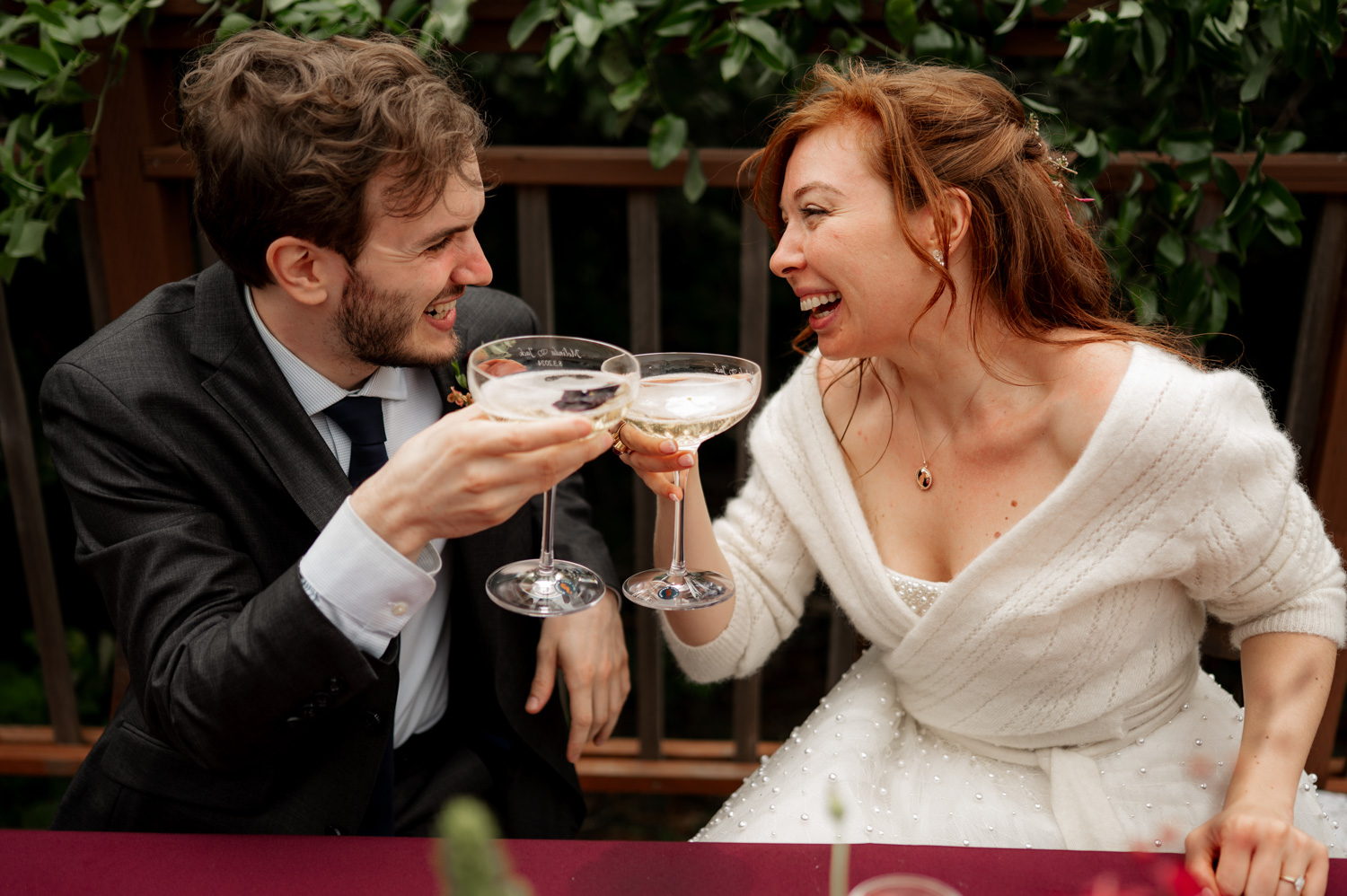 A joyful couple in formal attire clinks champagne glasses at an outdoor celebration, capturing a perfect moment for their wedding photos at the Yachats Inn.