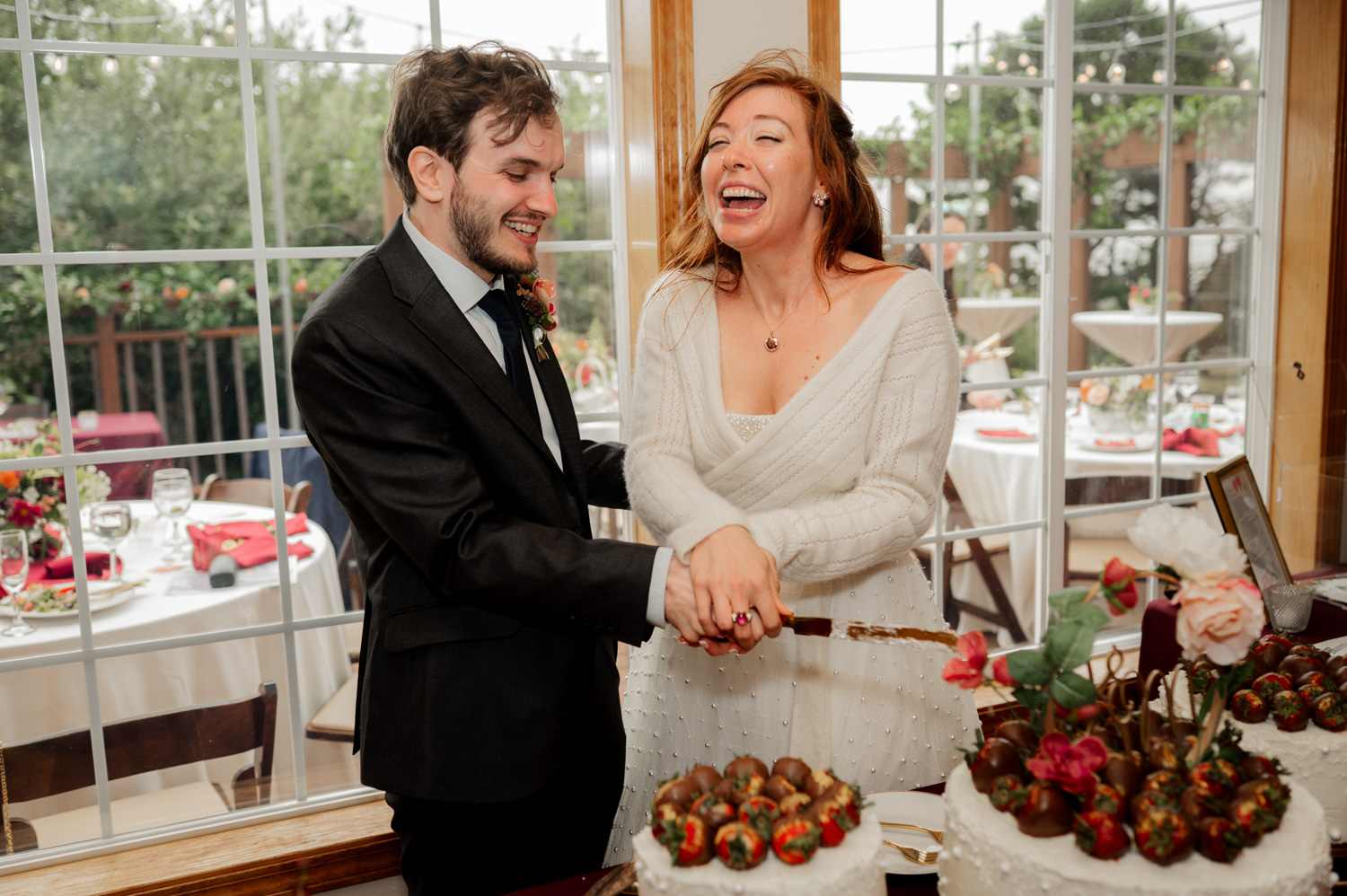 A couple joyfully cutting their cake together during their wedding celebration at the Yachats Inn.