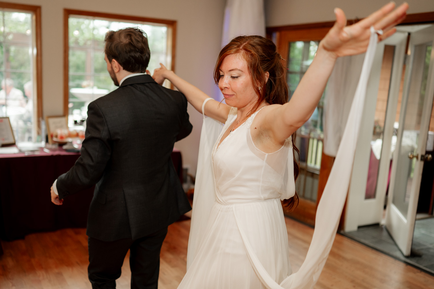 Bride and groom dancing indoors at the Yachats Inn; bride has arms lifted, wearing a white dress.