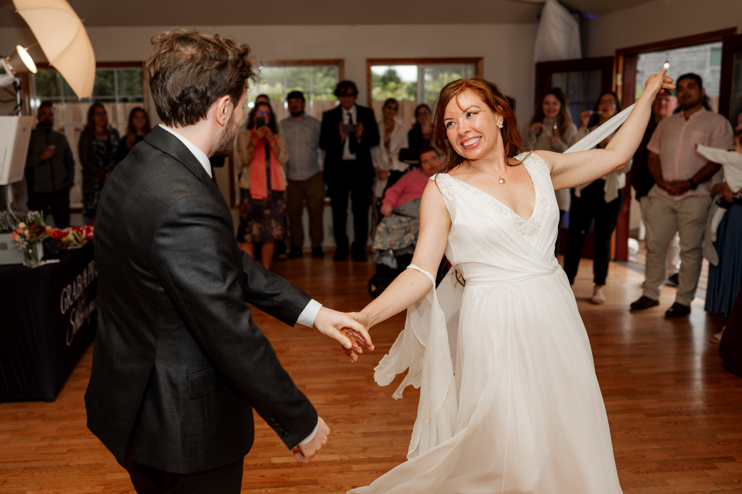 A couple dances joyfully at a wedding reception, surrounded by guests, with wedding photos capturing the magic at the Yachats Inn.