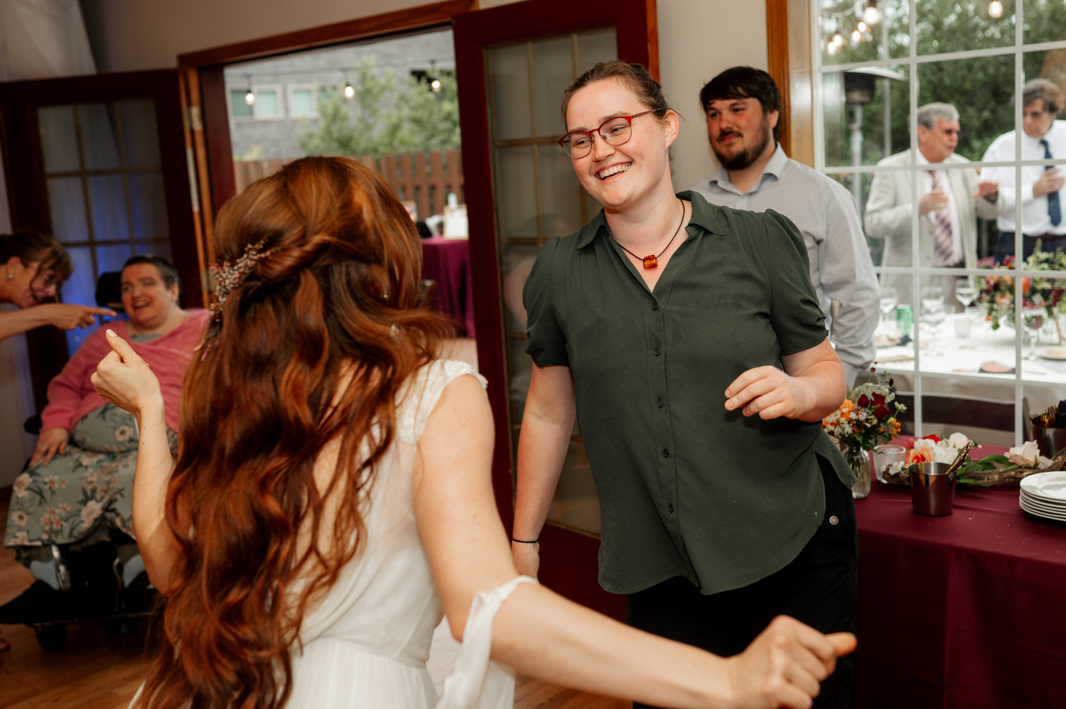 People dancing joyfully at an indoor event, with one person wearing a white dress and another in a green shirt, set against the backdrop of the Yachats Inn.